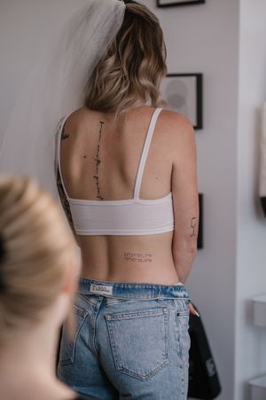 Back view showing spine tattoo and white crop top during a professional tattoo consultation.
