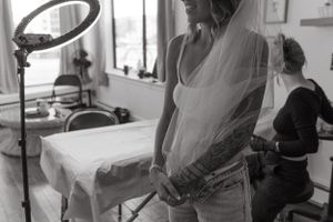 Black and white photo of a tattoo session preparation with ring light visible in studio setting.