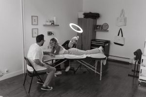 Black and white capture of tattoo artists working with client on massage table in professional studio.