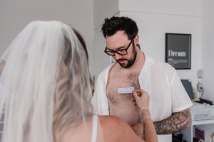 Intimate getting ready moment between couple during wedding preparations.