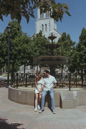 Vintage-style photo of couple by fountain with classic church architecture.