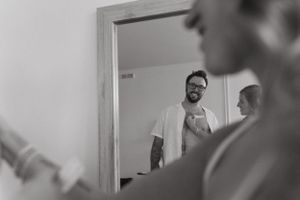 Mirror reflection captures candid wedding preparation moment.