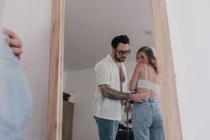 Casual wedding preparation moment captured through doorway reflection.