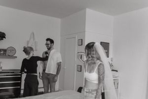 Black and white candid photo of wedding preparation in indoor setting.