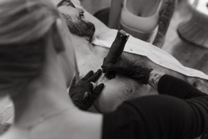 Black and white closeup of tattoo artist working on client.