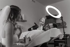 Black and white photo of a tattoo session with artistic ring lighting illuminating the workspace.