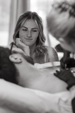 Black and white portrait during a professional tattoo session showing artistic focus and concentration.