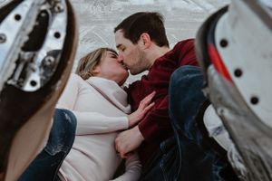 A couple sharing a romantic kiss while ice skating, framed by their skates.