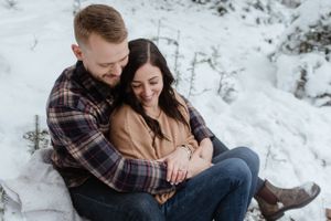Cozy winter couple portrait in snowy setting with intimate embrace.