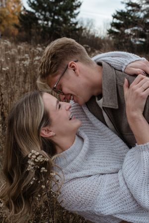 Couple sharing a joyful moment while lying in tall autumn grass.