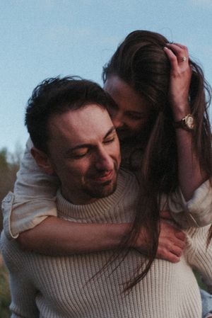 An intimate candid moment of laughter and joy captured outdoors in knit sweaters.