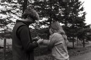 A black and white capture of a romantic moment on a tree-lined path.