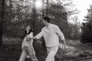 Playful couple running and holding hands in forest setting.