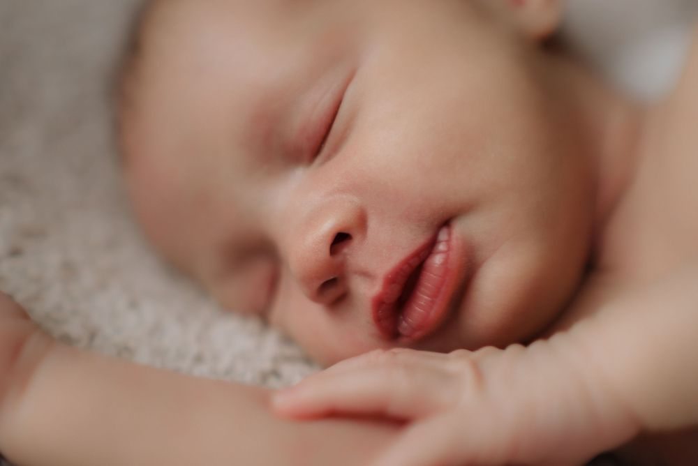 Close-up of a newborn baby sleeping peacefully, showing delicate facial features and soft skin.