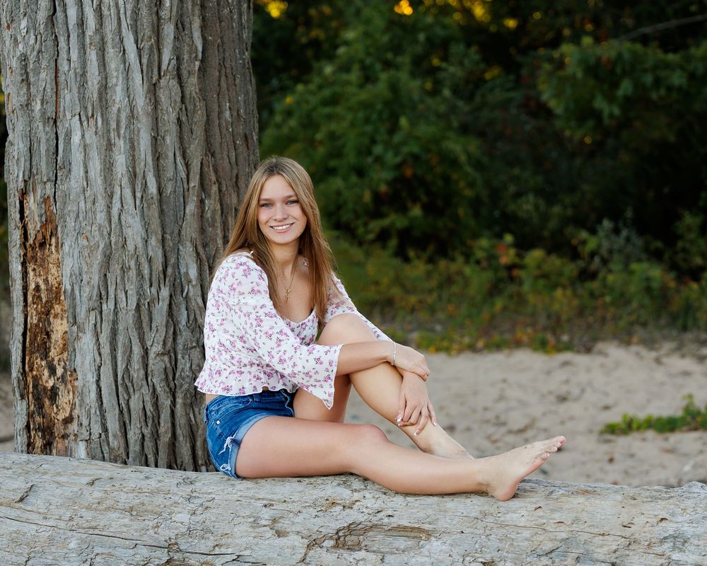Portrait series showing different poses near a tree trunk on a sandy beach at sunset.