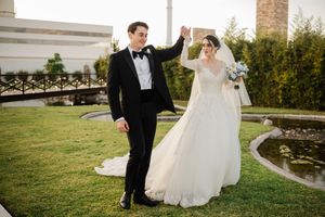 A bride and groom share a romantic moment on a grassy lawn during their outdoor wedding celebration.