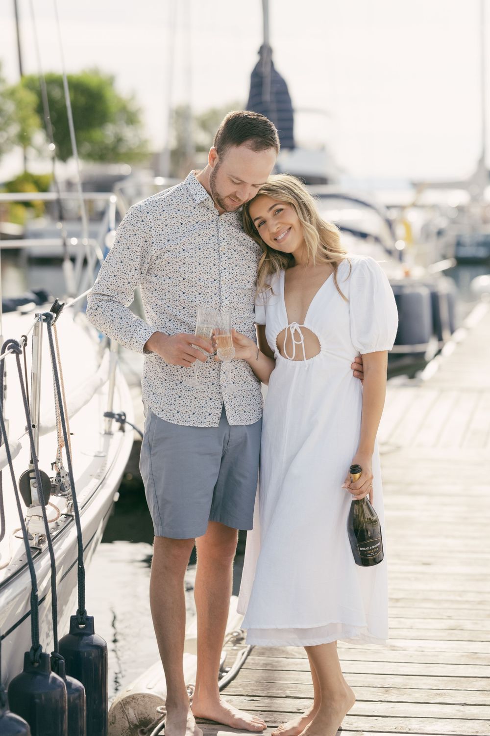 Couple sharing champagne on wooden dock by marina.