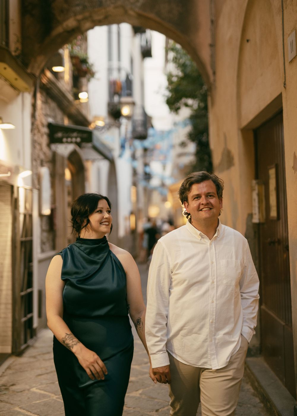 Candid sequence of couple laughing and walking through European alleyway.