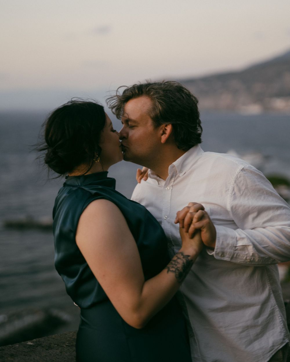 Romantic sunset photoshoot with couple dancing by the ocean.