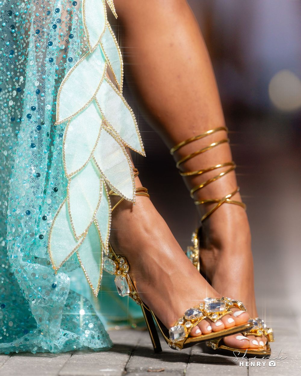 Elegant gold spiral ankle bracelet and jeweled sandals paired with a sparkly turquoise and white leaf-patterned gown.