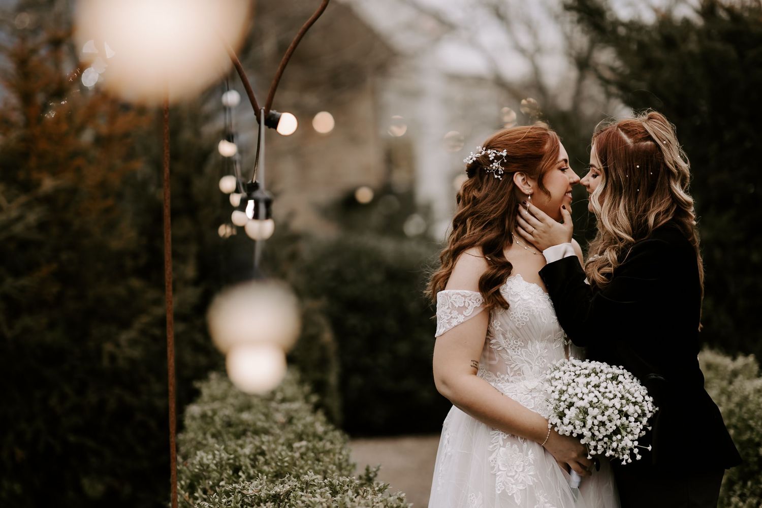 Romantic outdoor wedding scene with white baby's breath bouquet and glowing string lights at dusk.
