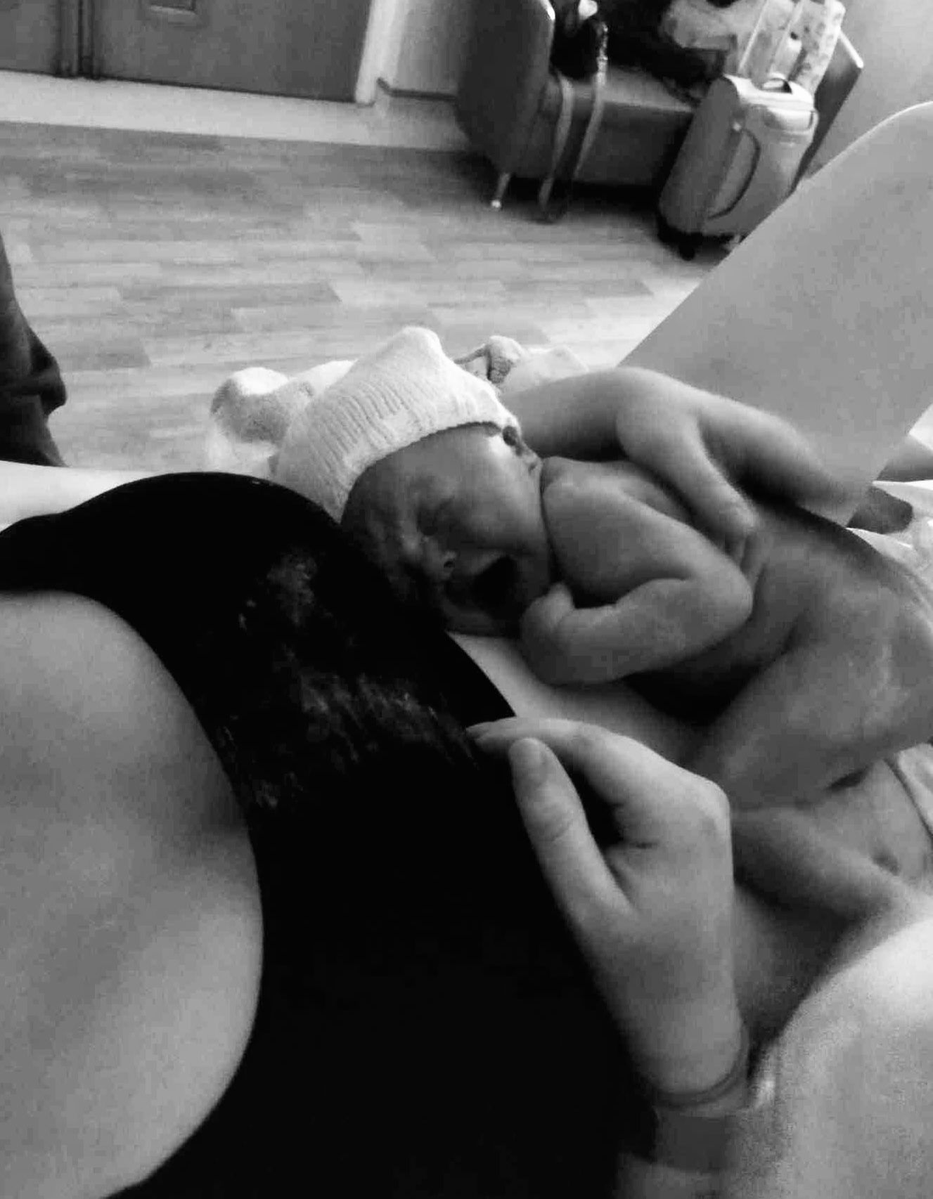 A black and white hospital scene showing a birthing moment with medical professionals attending to a patient on a bed.