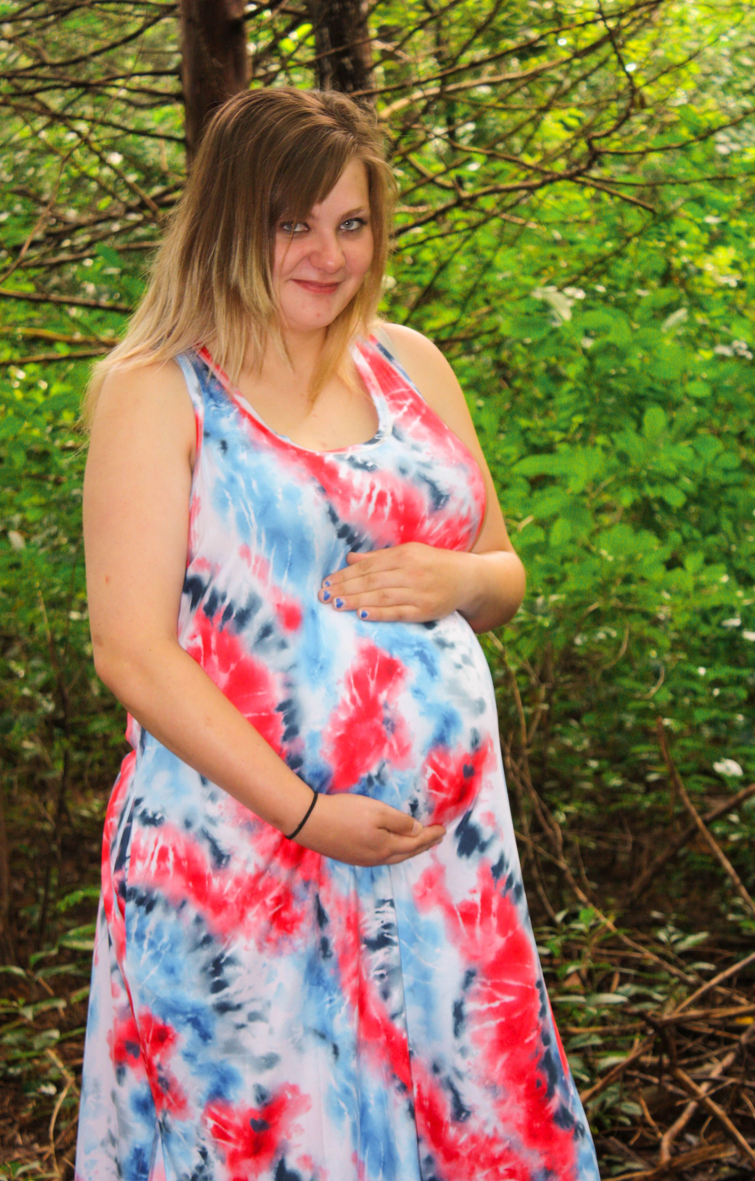 A tie-dye dress in red, white and blue creates a vibrant pattern against green foliage.