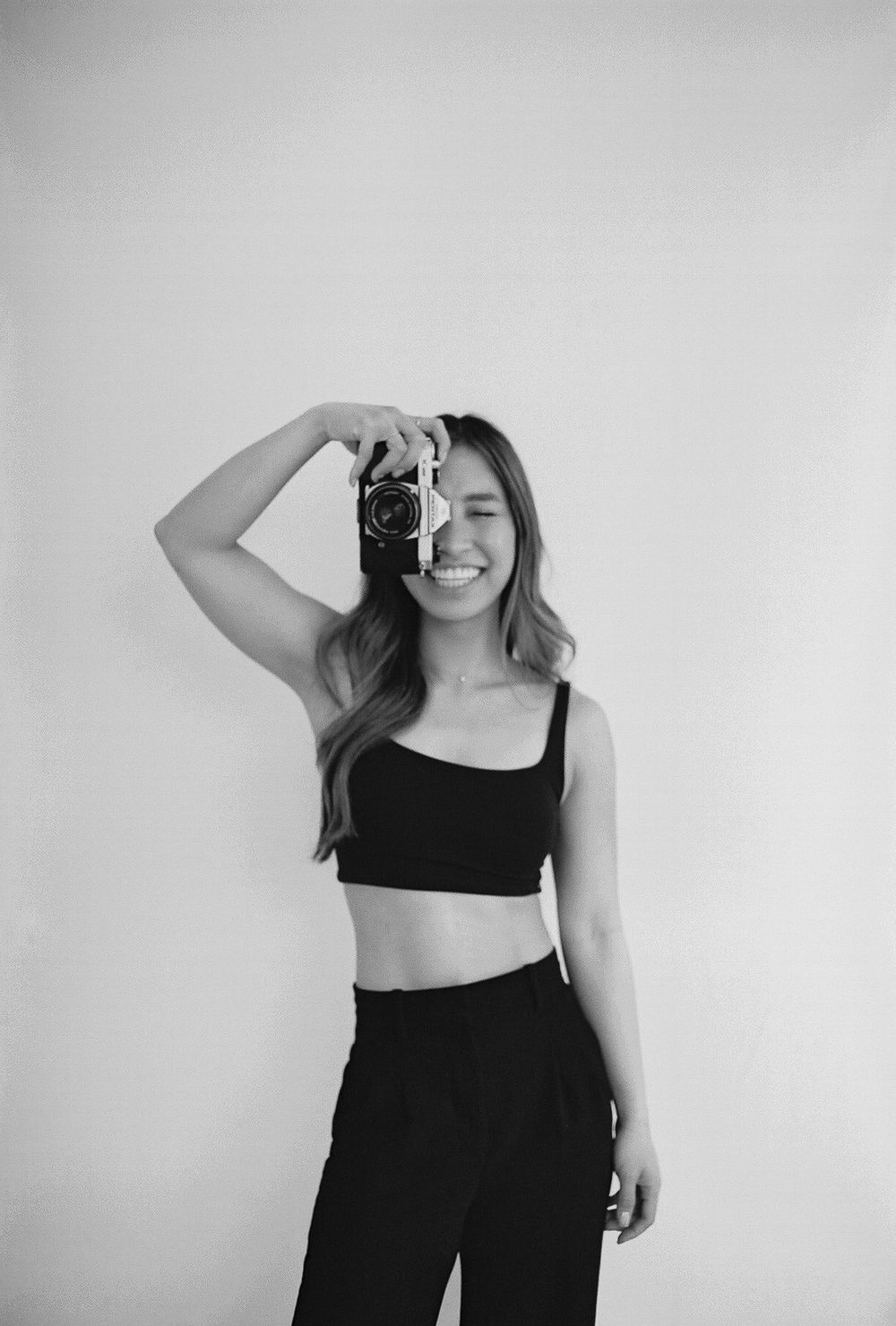 Minimalist black and white self-portrait series with a camera against white background.
