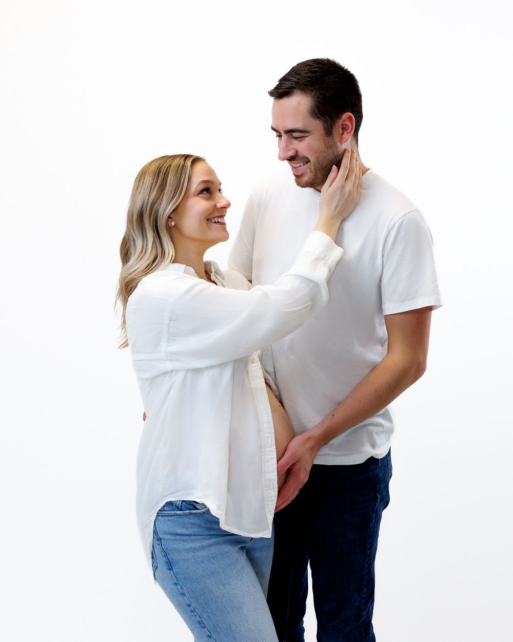 A couple in white shirts and jeans sharing playful moments together in a photo series.