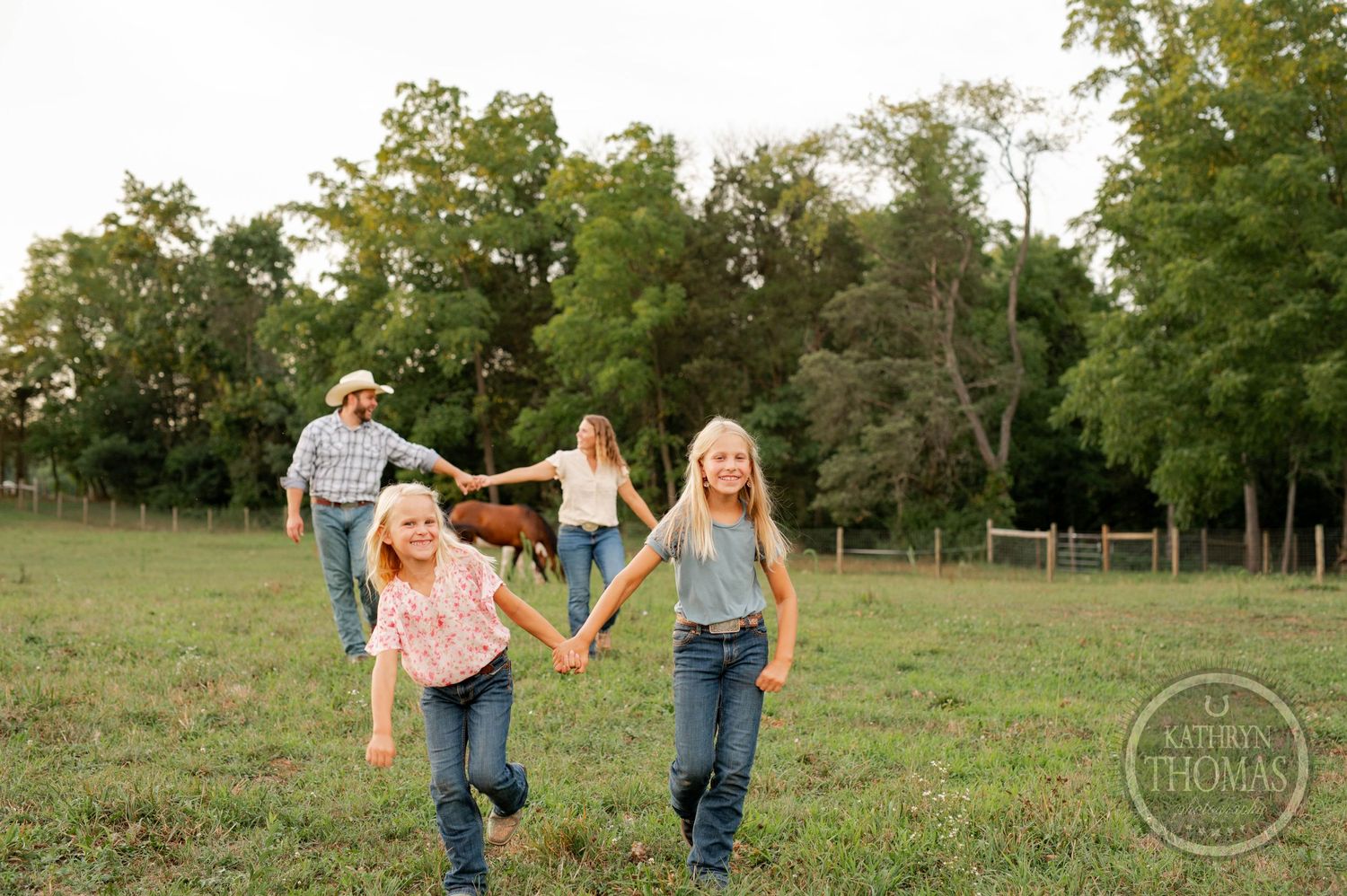 Joyful group holding hands while running through a sunlit grassy field.