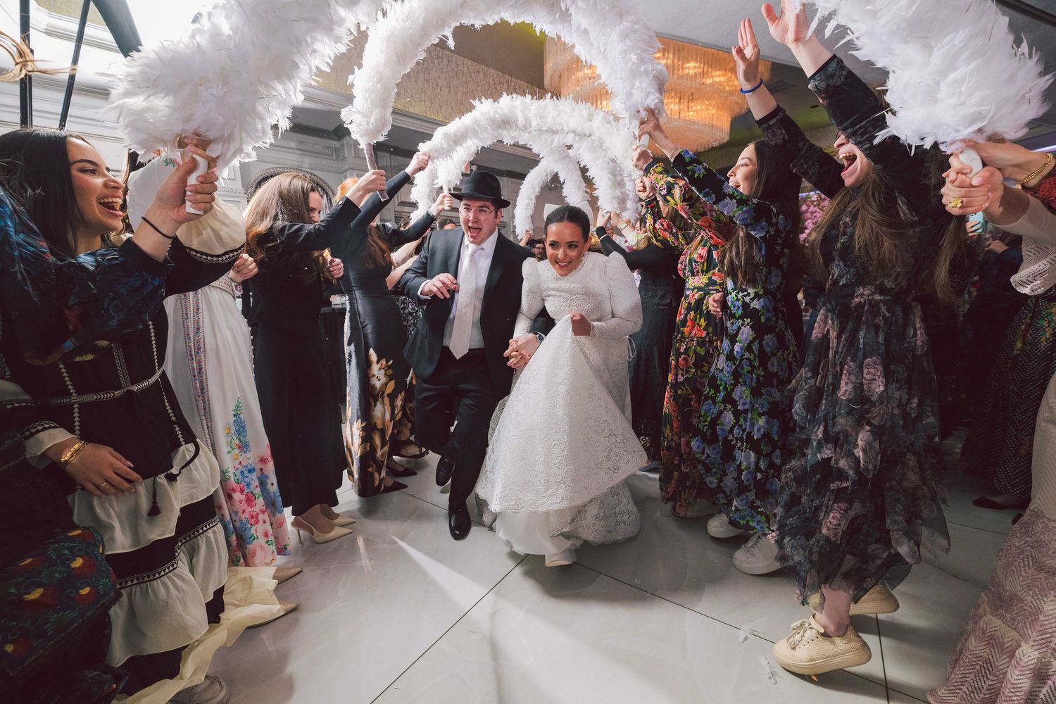 Wedding celebration with guests creating sparkler tunnel effect indoors.