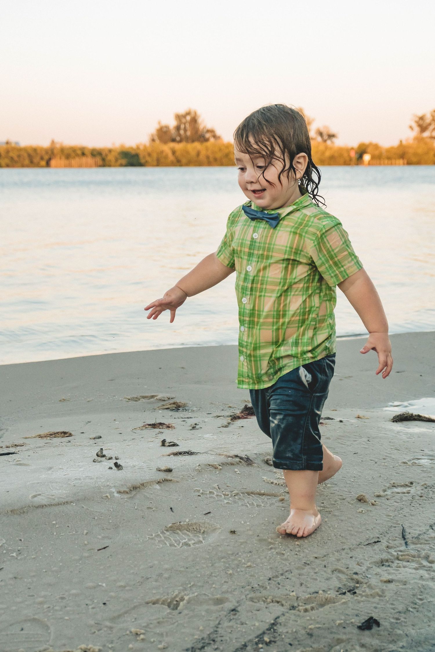 Wild toddler running barefoot through the sand during a candid family session in Palm Bay.