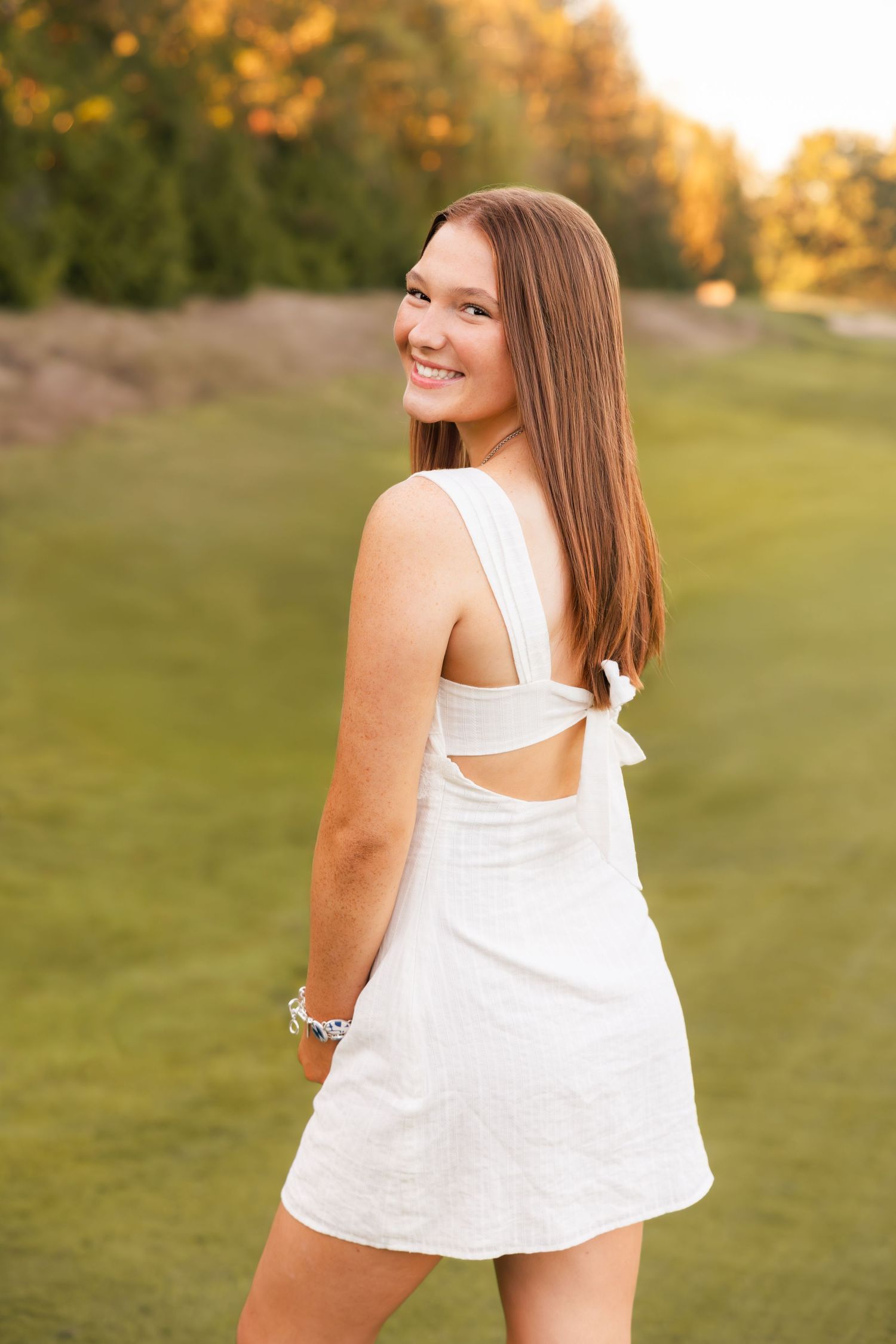 Four sequential outdoor portrait photos in warm sunlight showing a white sleeveless top against a green grassy background.
