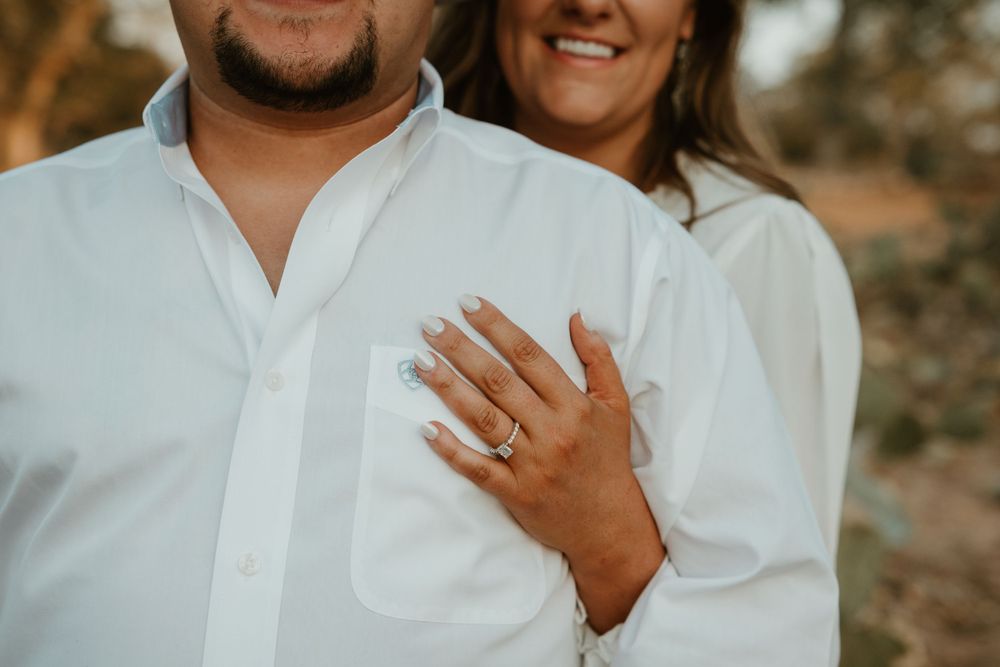 Close up of hands showing engagement ring with white clothing.