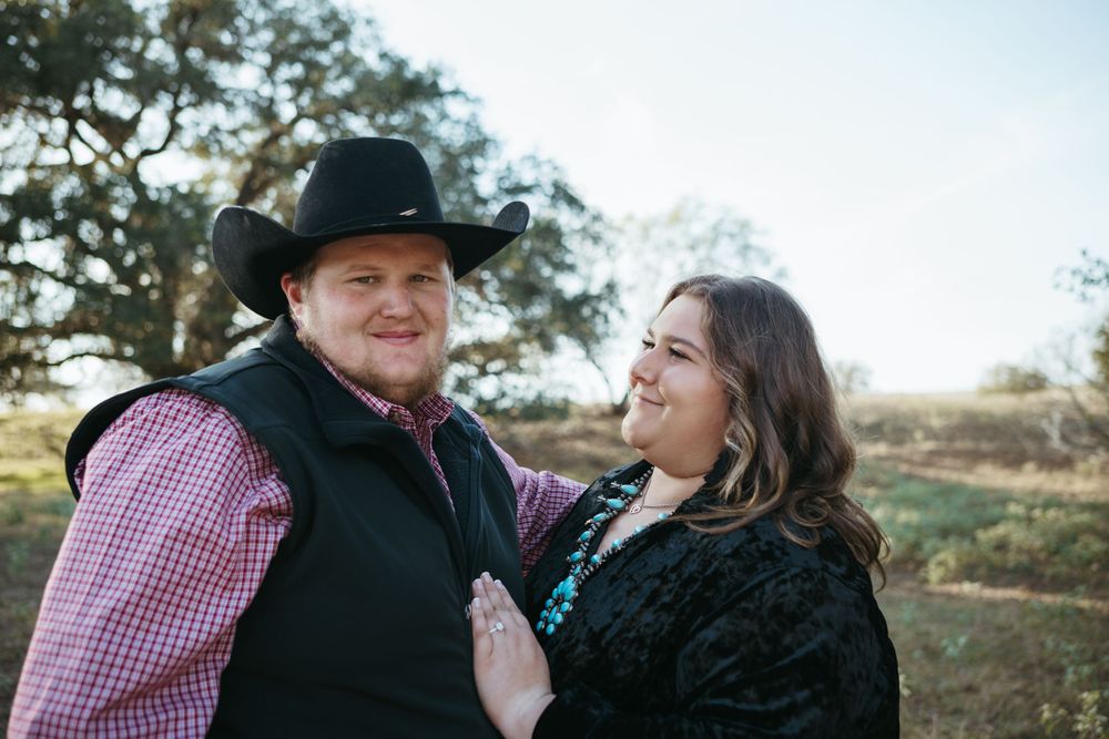 A couple dressed in western attire sharing a joyful moment outdoors at sunset.