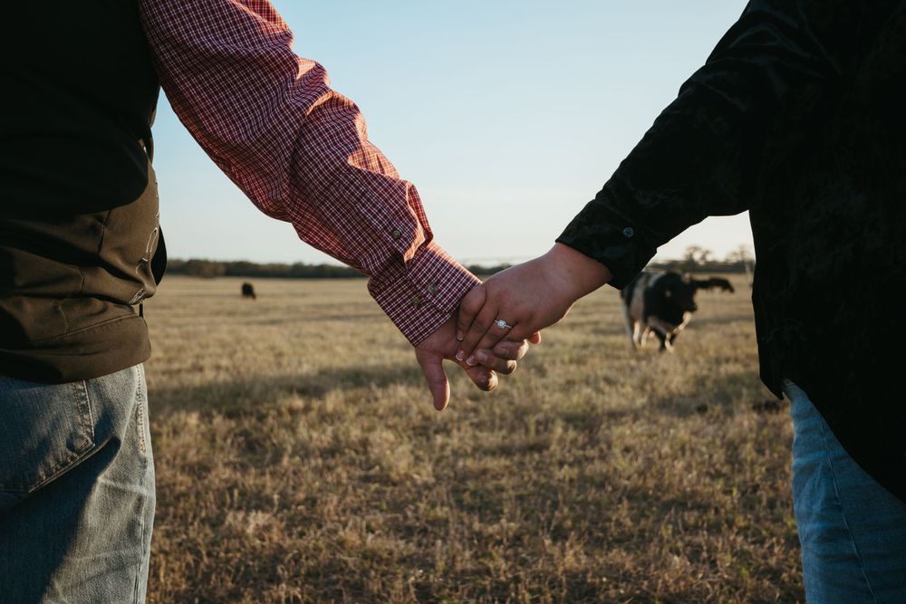 Close-up shot of intertwined hands against a golden field backdrop.