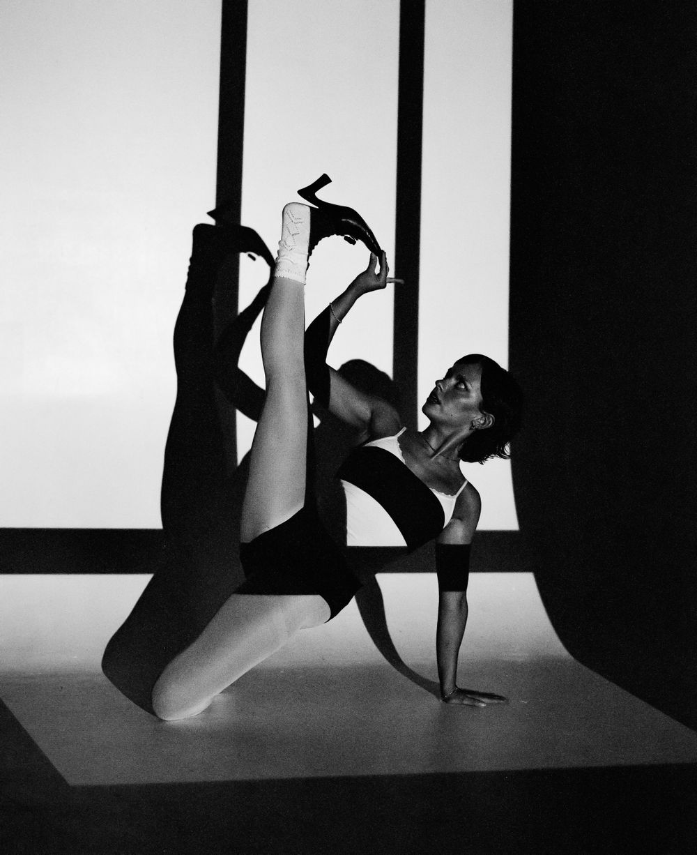 Dynamic dance pose captured in black and white with geometric lighting elements.