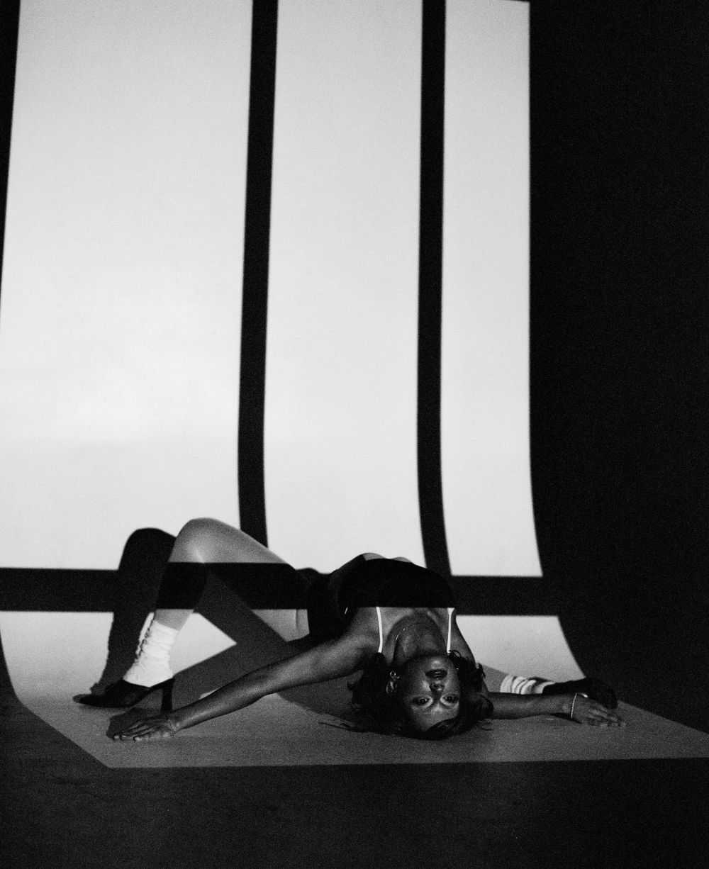 Artistic black and white photo of dancer in reclining pose with dramatic lighting.