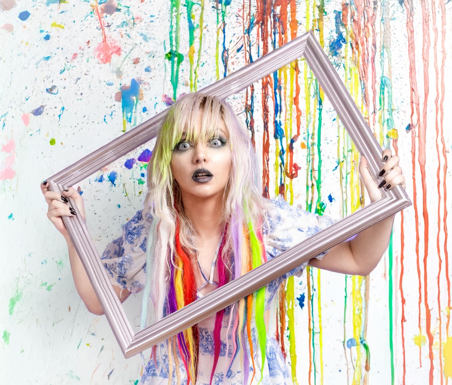Creative portrait with colorful dripping paint backdrop and decorative frame prop.