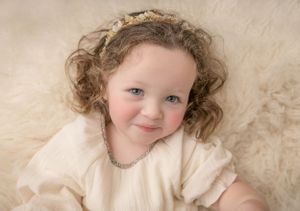 A series of connected photos showing a young child with curly hair lying on cream-colored fabric in different poses.