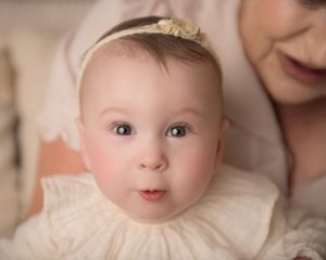A series of close-up photos showing a baby's sweet expressions while wearing a cream-coloured outfit.