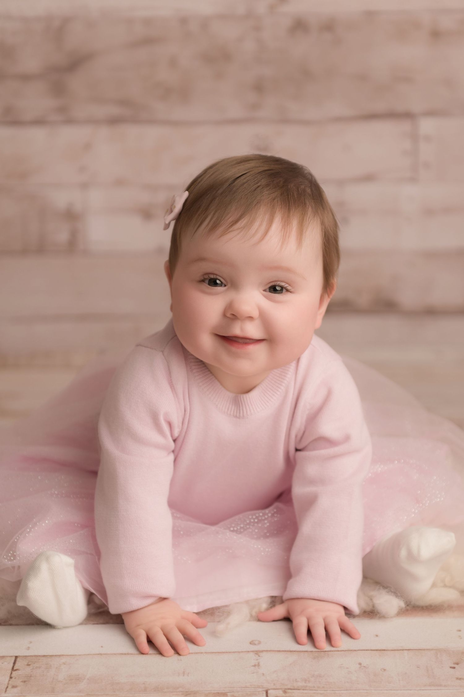 A baby smiles candidly at her sitter milestone photography session.