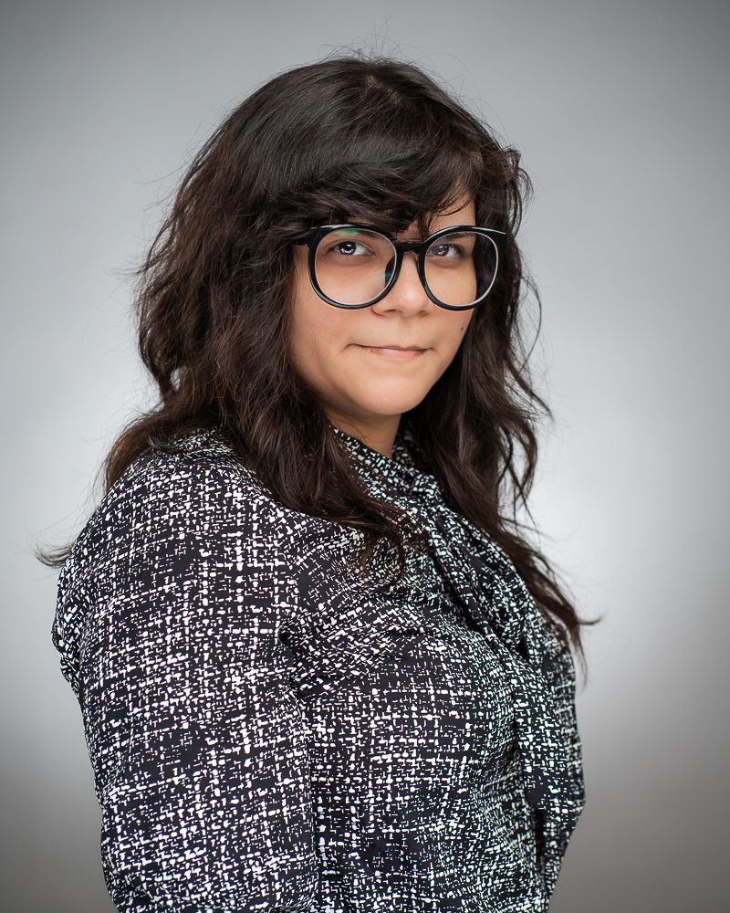 Studio portrait of someone wearing glasses and a patterned blazer.