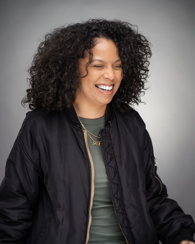 Casual portrait of someone in a black jacket with curly hair.