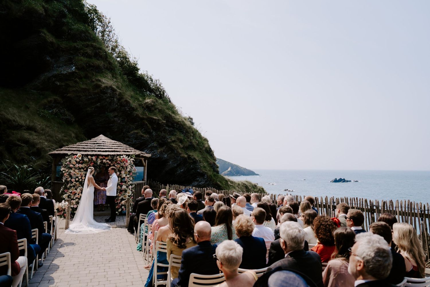Bride and Groom in front of floral arch next to the sea at Tunnels Beach Wedding Venue in North Devon