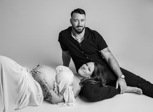 Black and white portrait of two people in relaxed poses during a maternity photo session.