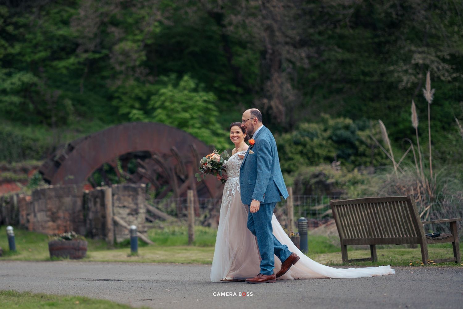A couple dances together outdoors at a park with a rustic denim and gown combination.