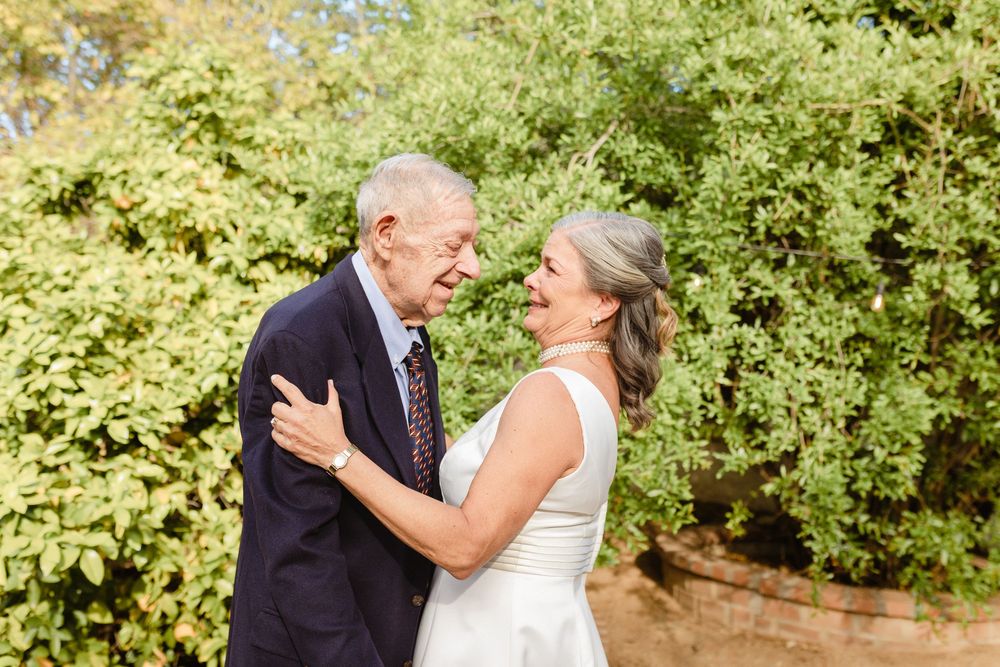 A dad and daughter share joyful moment together in a lush garden setting.