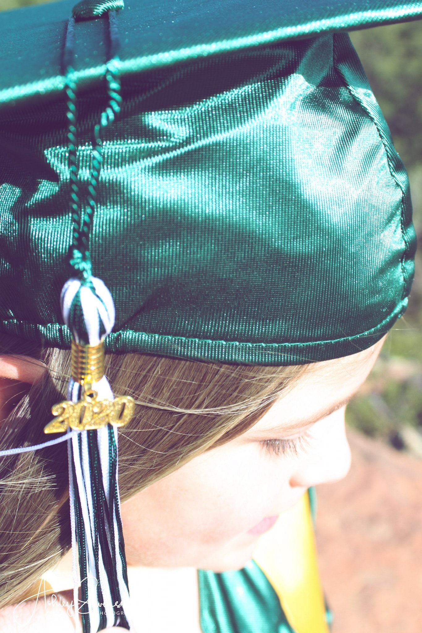 Close-up of green 2020 graduation cap with black and white tassel worn by blonde graduate.
