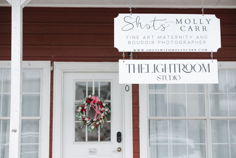 Red building exterior with white door featuring Shots by Molly Carr maternity boudoir photographer and The Lightroom Studio signs.